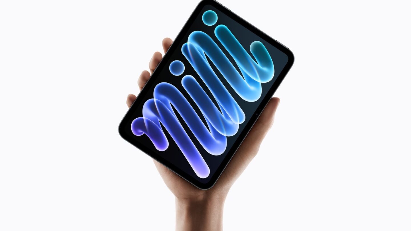 Hand holding the new iPad mini with an OLED display showing a blue abstract wallpaper