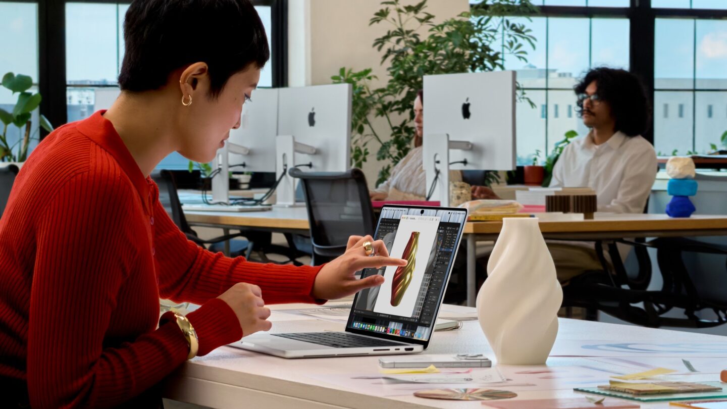 Person at an office desk touching the screen of the MacBook Pro with PROLED XDR Display