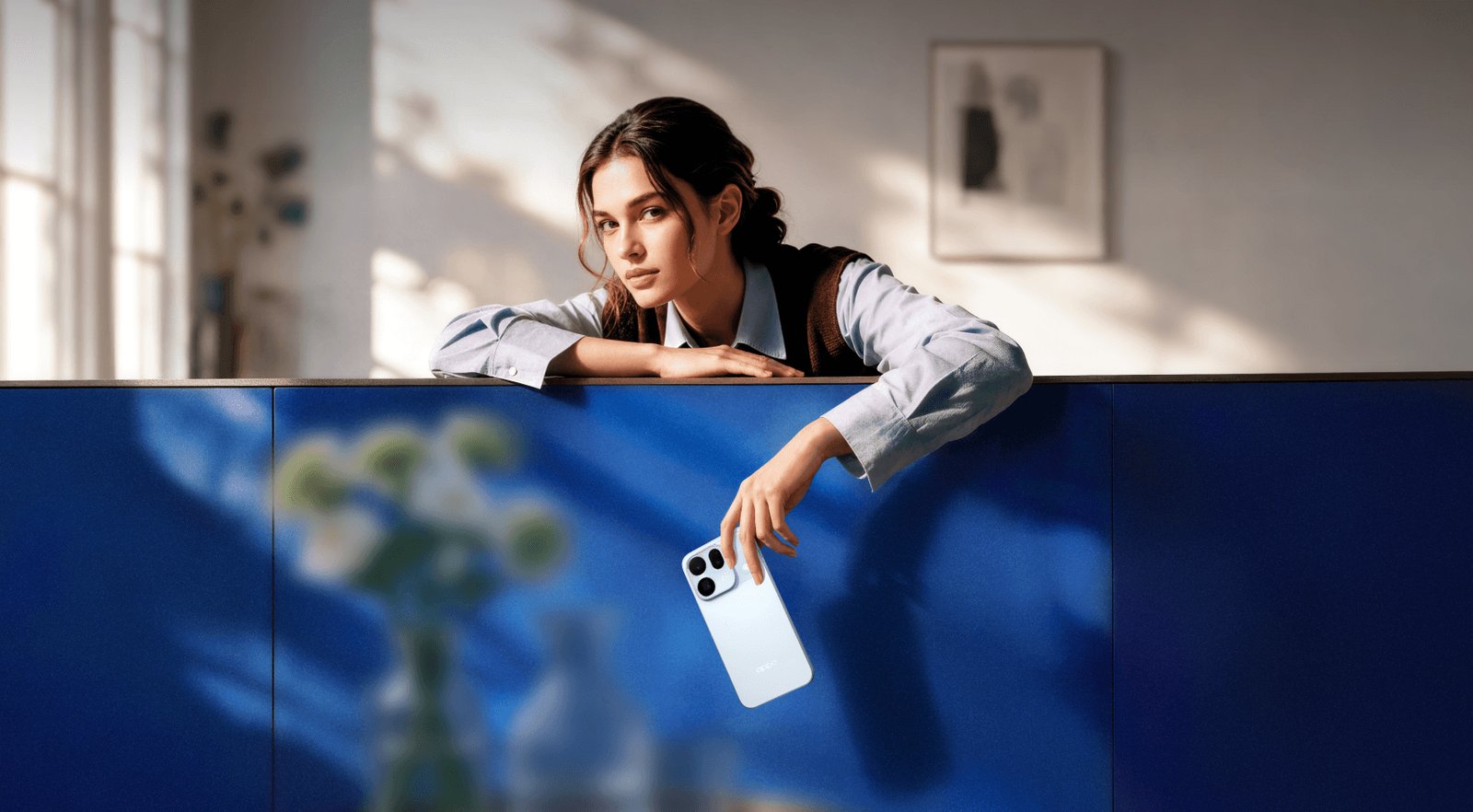 Woman leaning over a blue wall holding the OPPO Find X10 in Glacier Blue